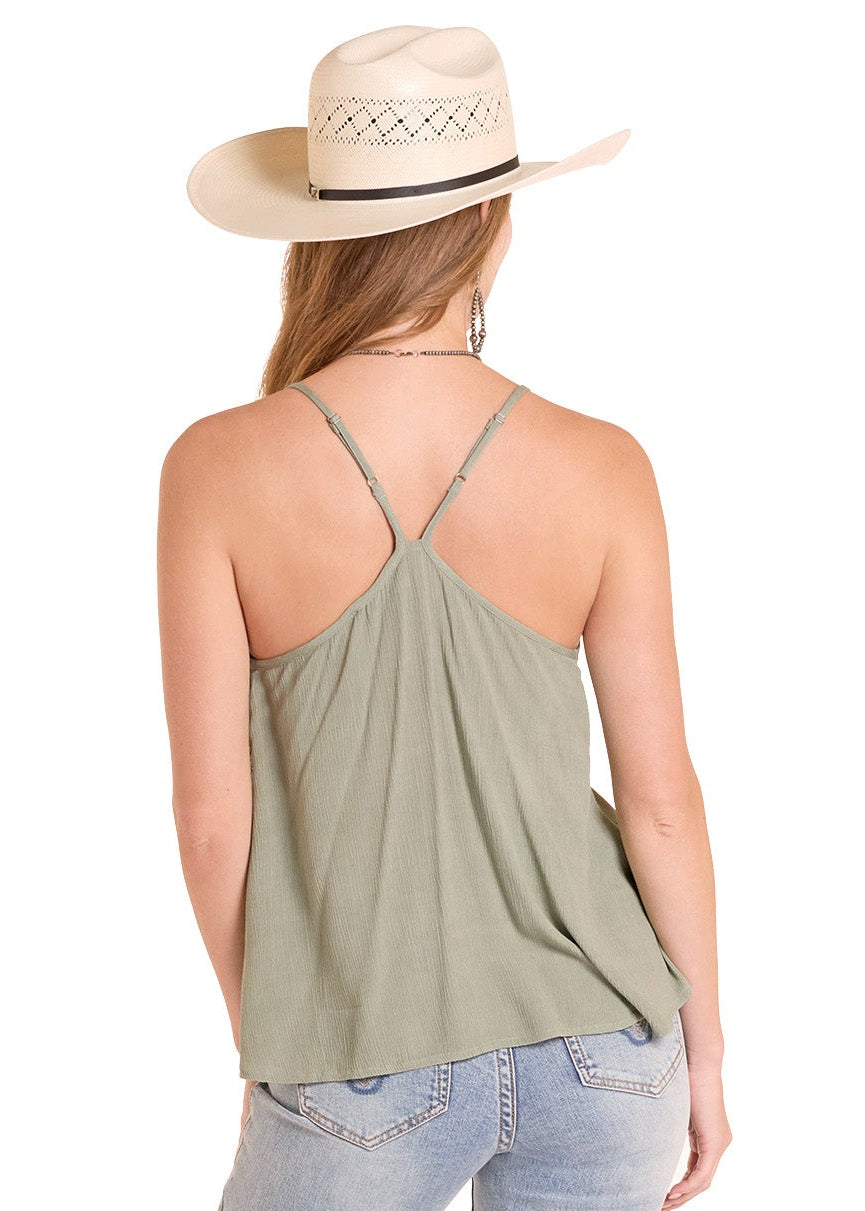 Woman wearing a green tank top and light blue jeans with a straw hat on a white background