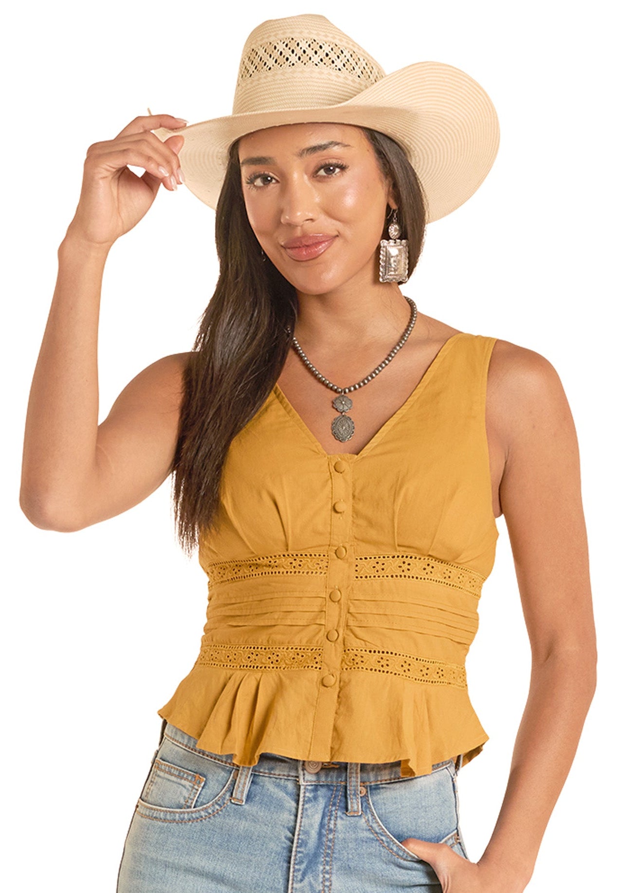 Woman wearing a mustard yellow top, blue jeans, and a beige cowboy hat on a white background