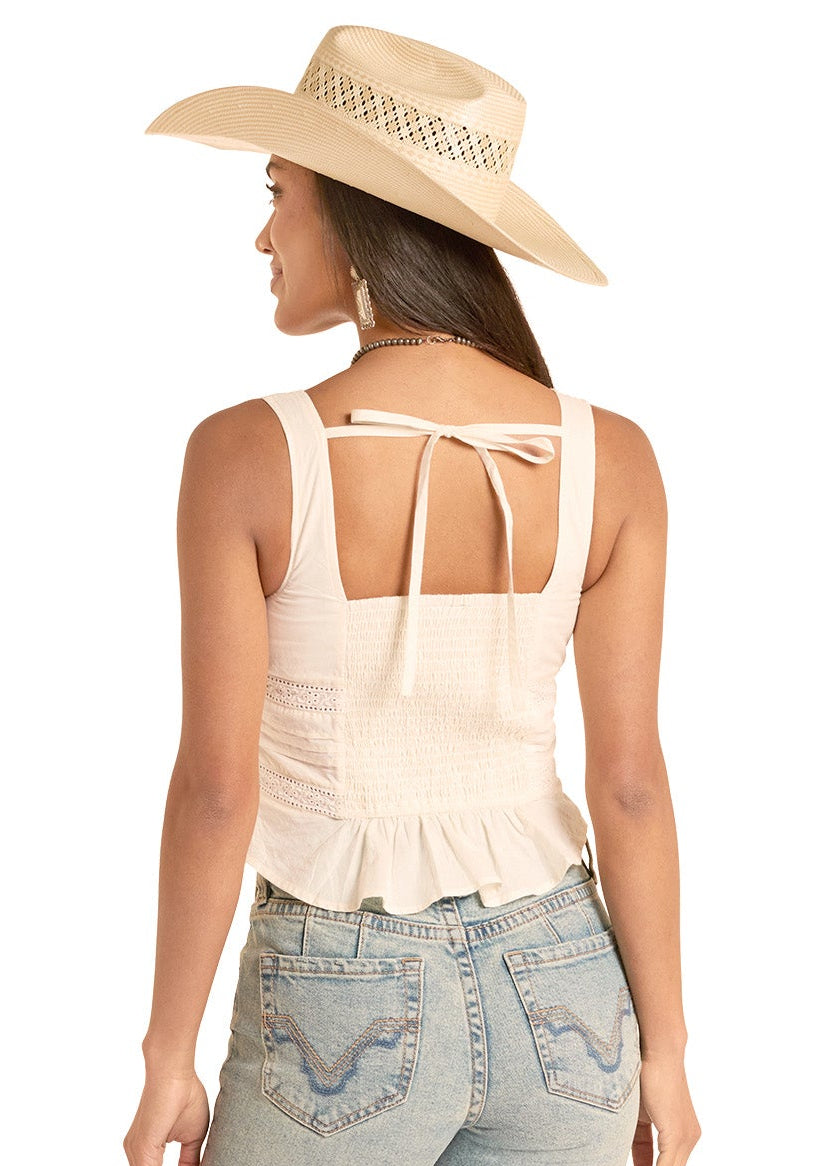 Woman wearing light blue jeans and a beige tank top with a straw hat on a white background