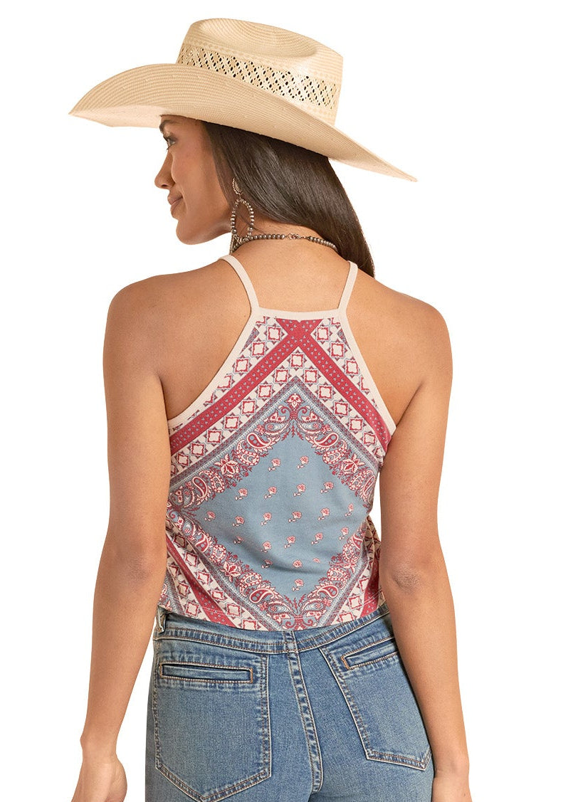 Woman wearing a patterned top and blue jeans with a beige hat on a white background
