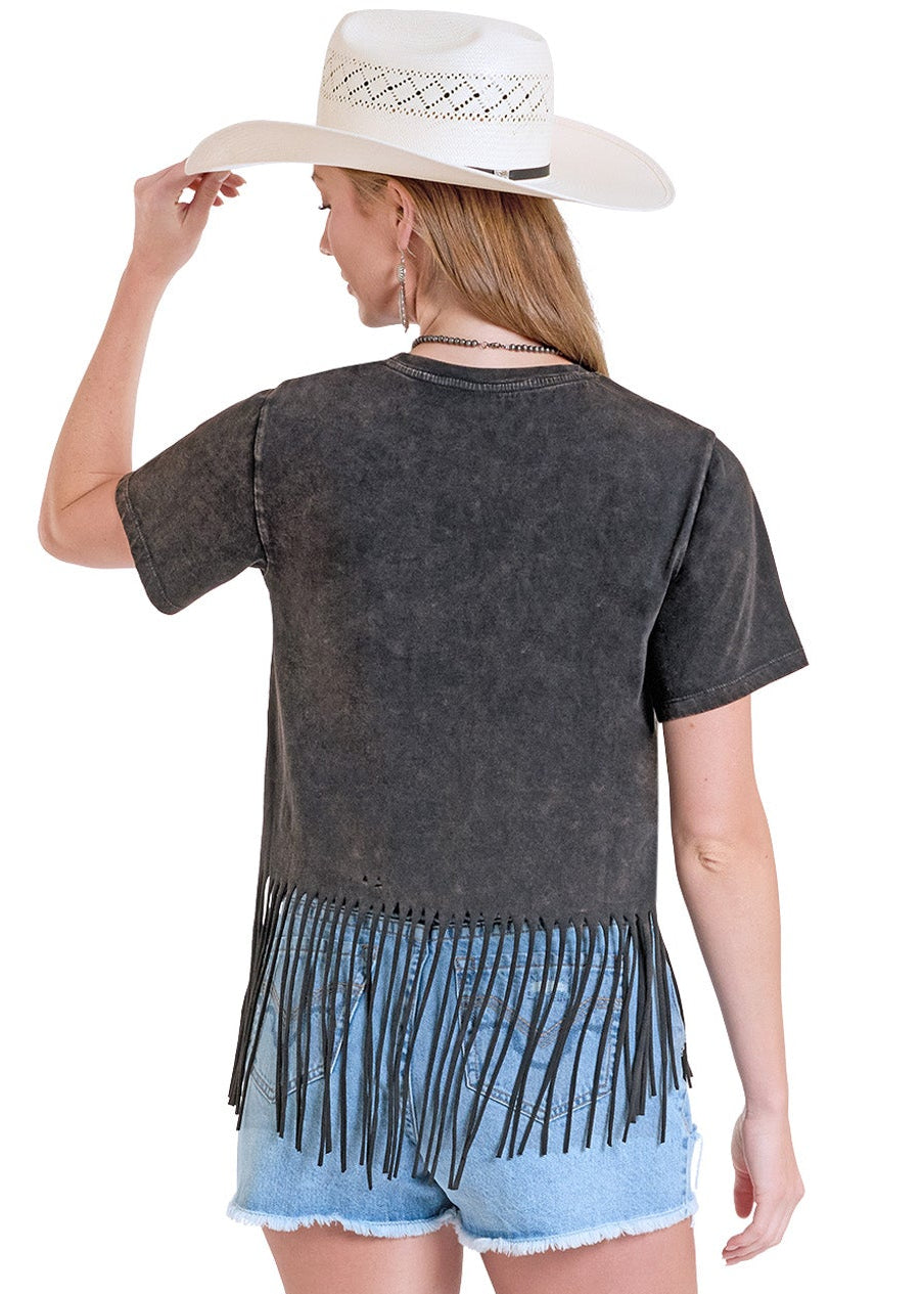 Woman wearing a black fringe top and light blue shorts with white cowboy boots on a white background