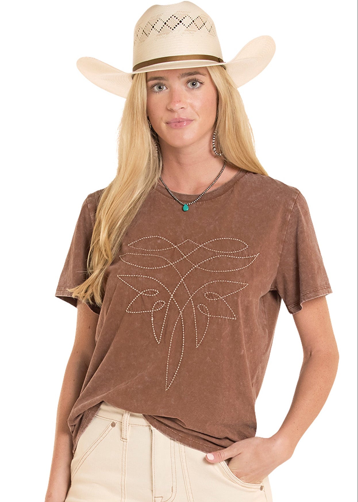 Woman wearing a brown t-shirt with a graphic design and a beige cowboy hat on a white background