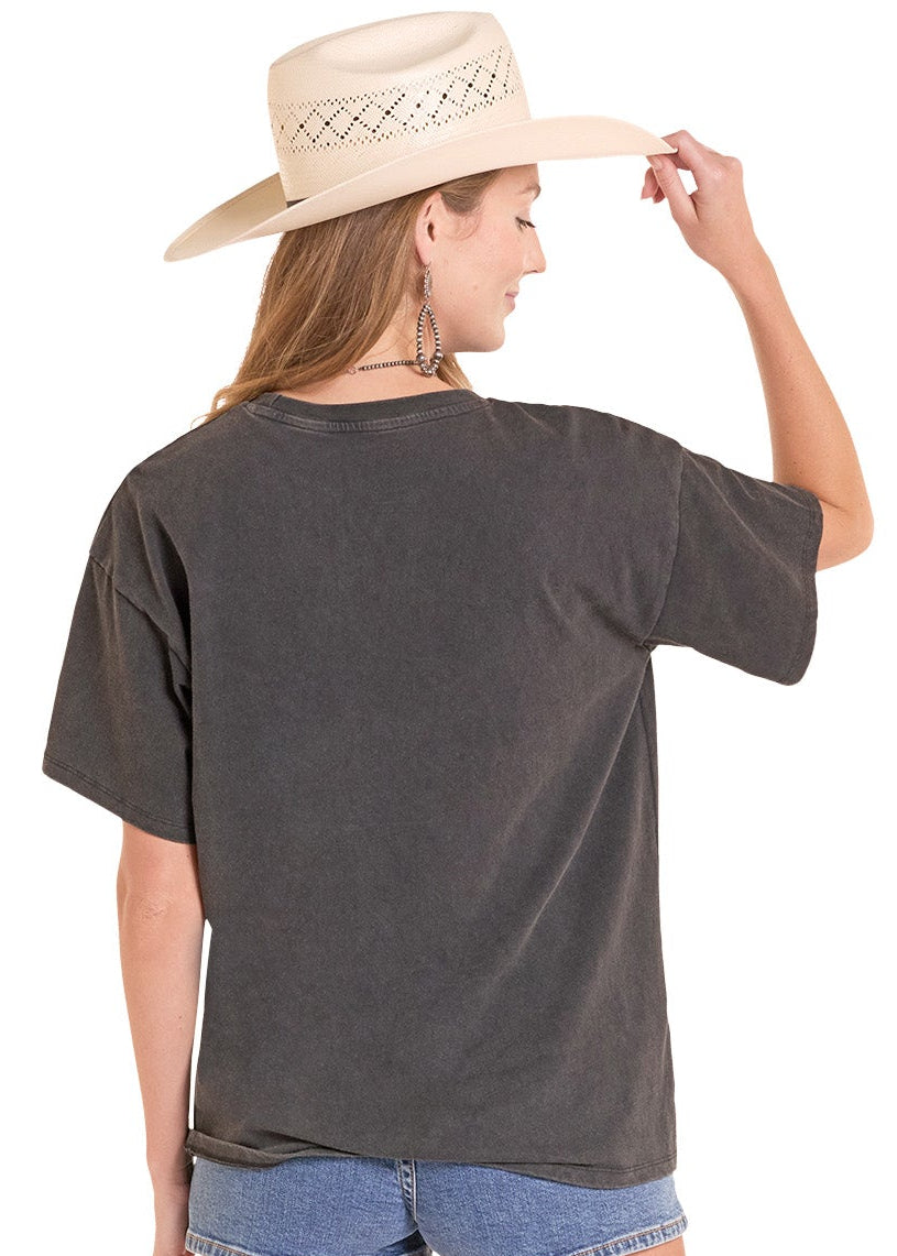 Woman wearing a dark gray oversized t-shirt, denim shorts, and white cowboy boots on a white background
