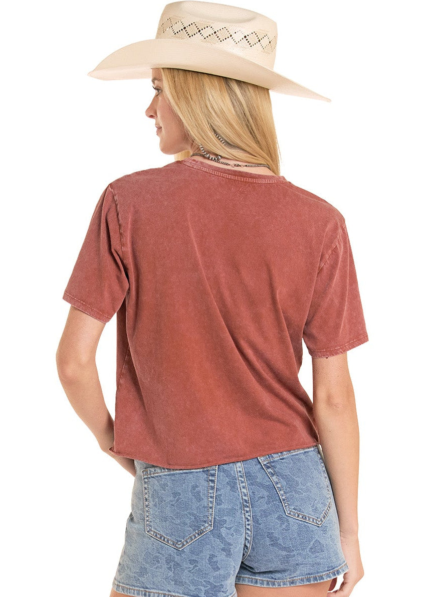 Person wearing a rust-colored t-shirt, denim shorts, and white cowboy boots on a white background