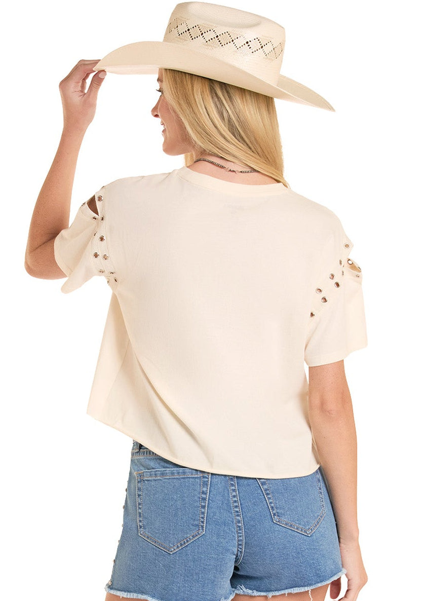 Woman wearing a beige top, denim shorts, and cowboy boots on a white background