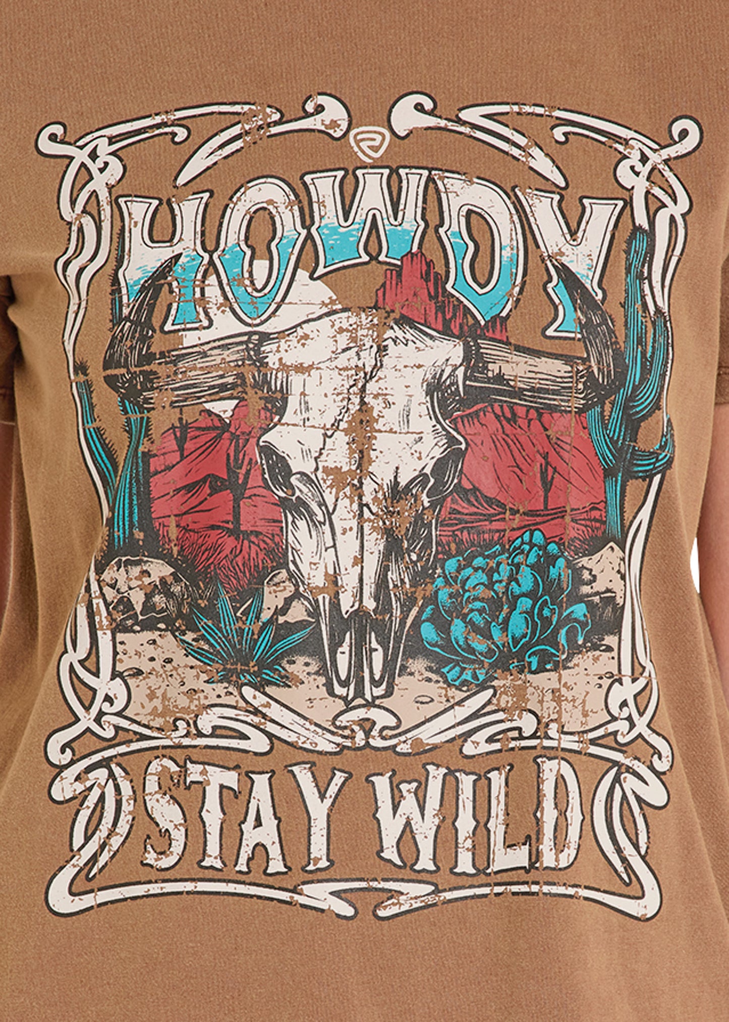 T-shirt with a graphic design of a skull, cacti, and 'Howdy Stay Wild' text on a brown background.