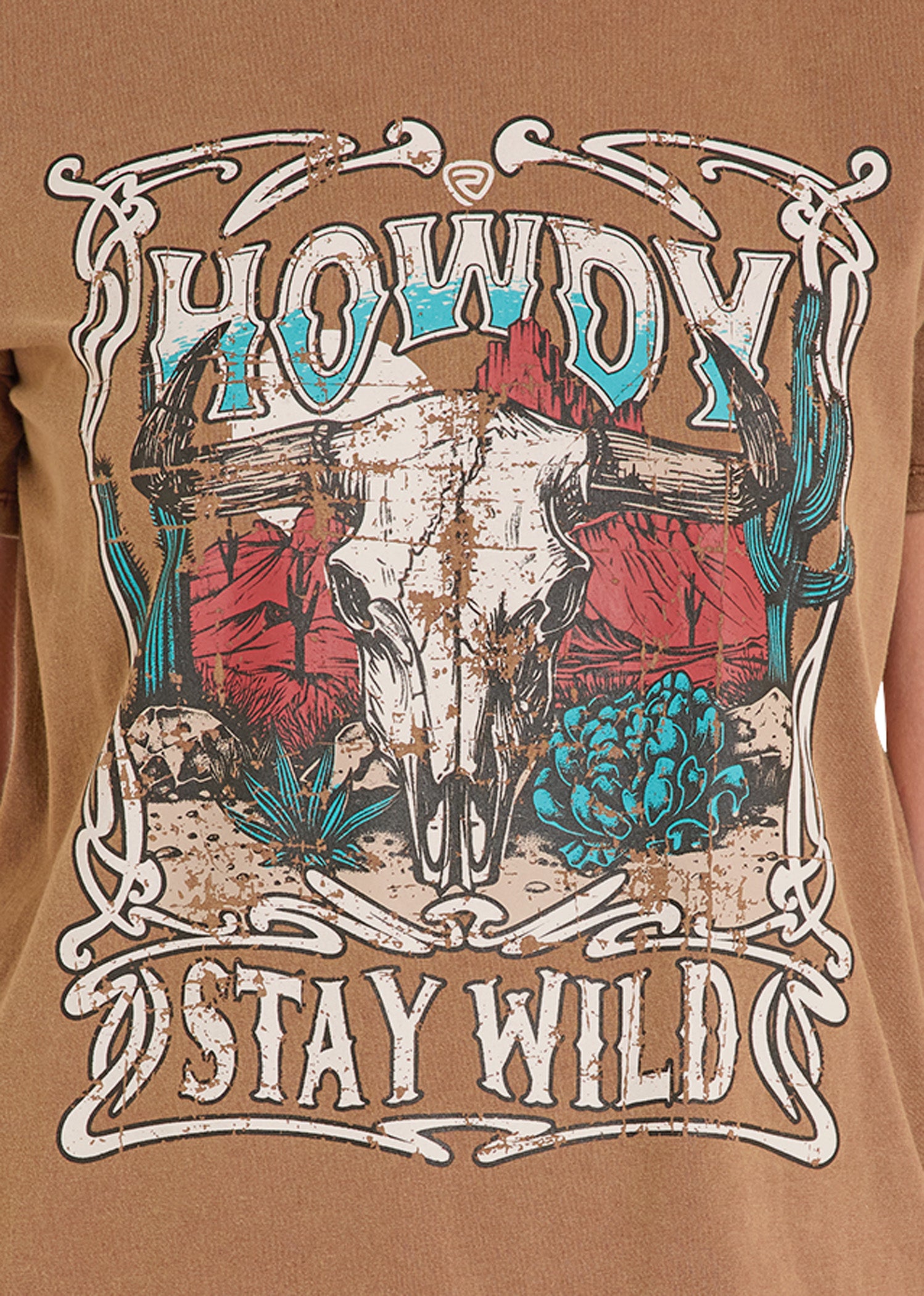 T-shirt with a graphic design of a skull, cacti, and 'Howdy Stay Wild' text on a brown background.