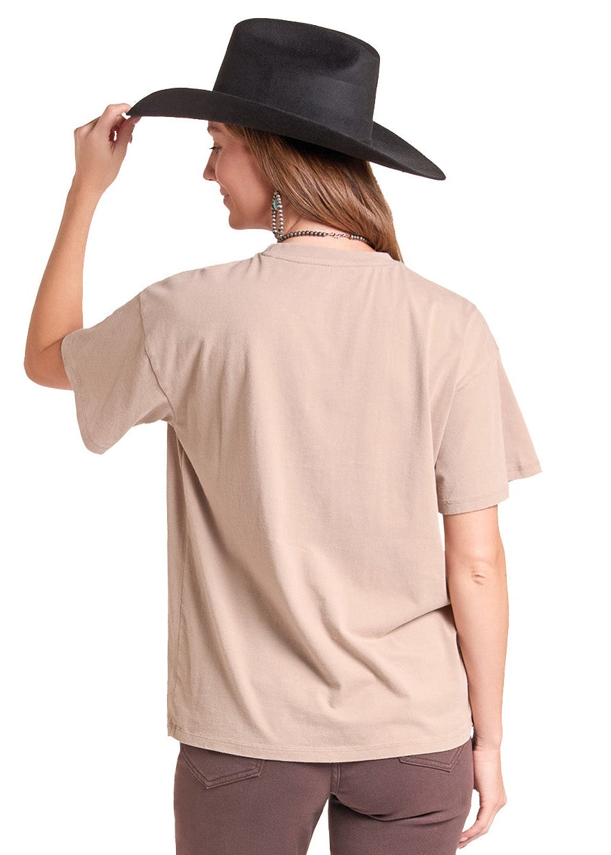 A woman shown from the back wearing a beige short-sleeve t-shirt, brown flared pants, and a black cowboy hat against a plain white background.