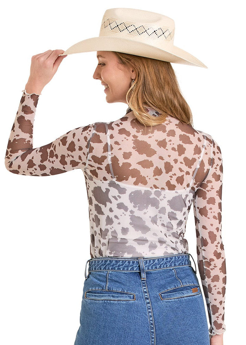 Woman wearing a patterned long-sleeve top and blue jeans with a cowboy hat on a white background