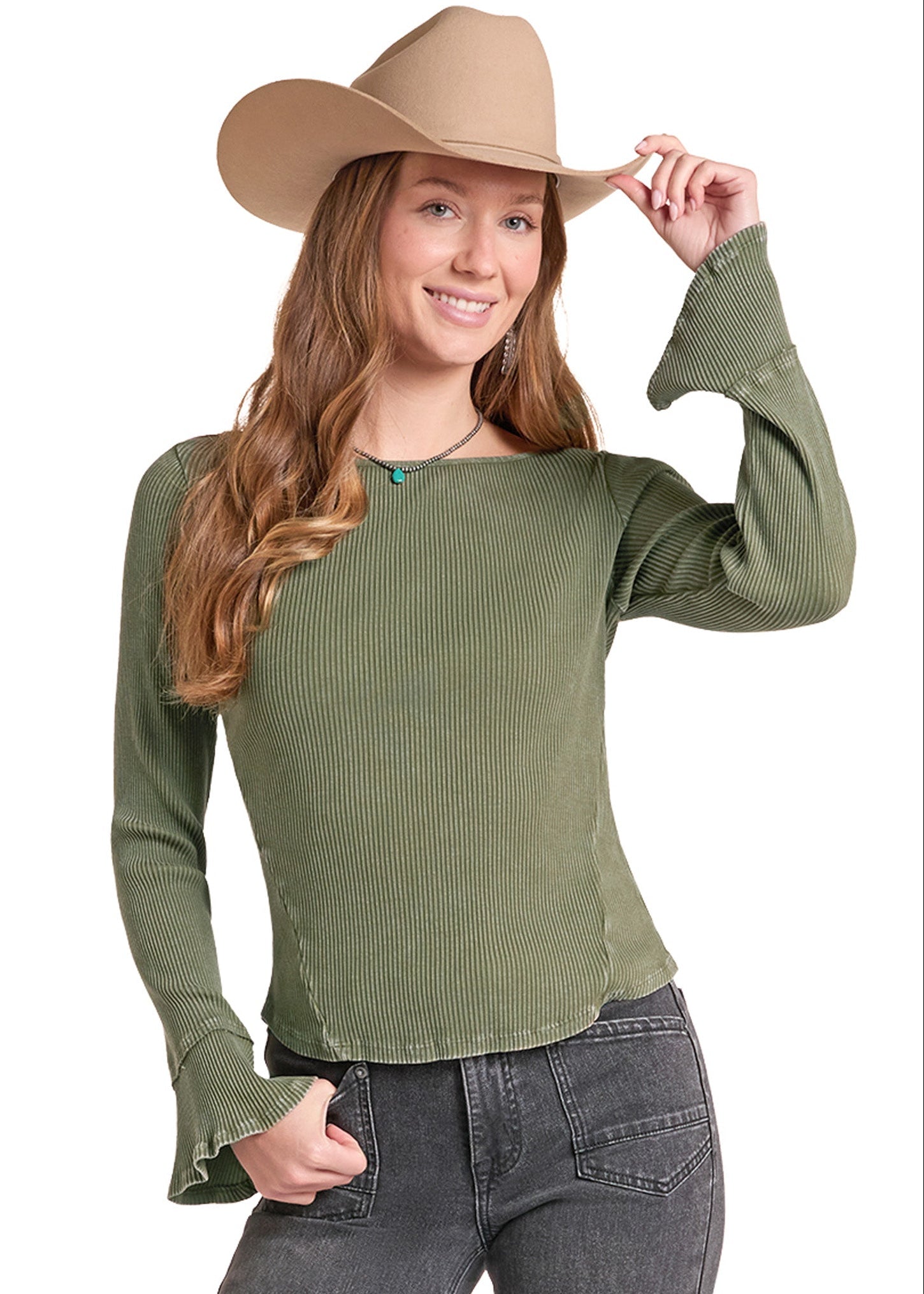 A woman wearing an olive green ribbed long-sleeve top with flared cuffs, paired with dark gray jeans and a tan cowboy hat, posing against a white background.