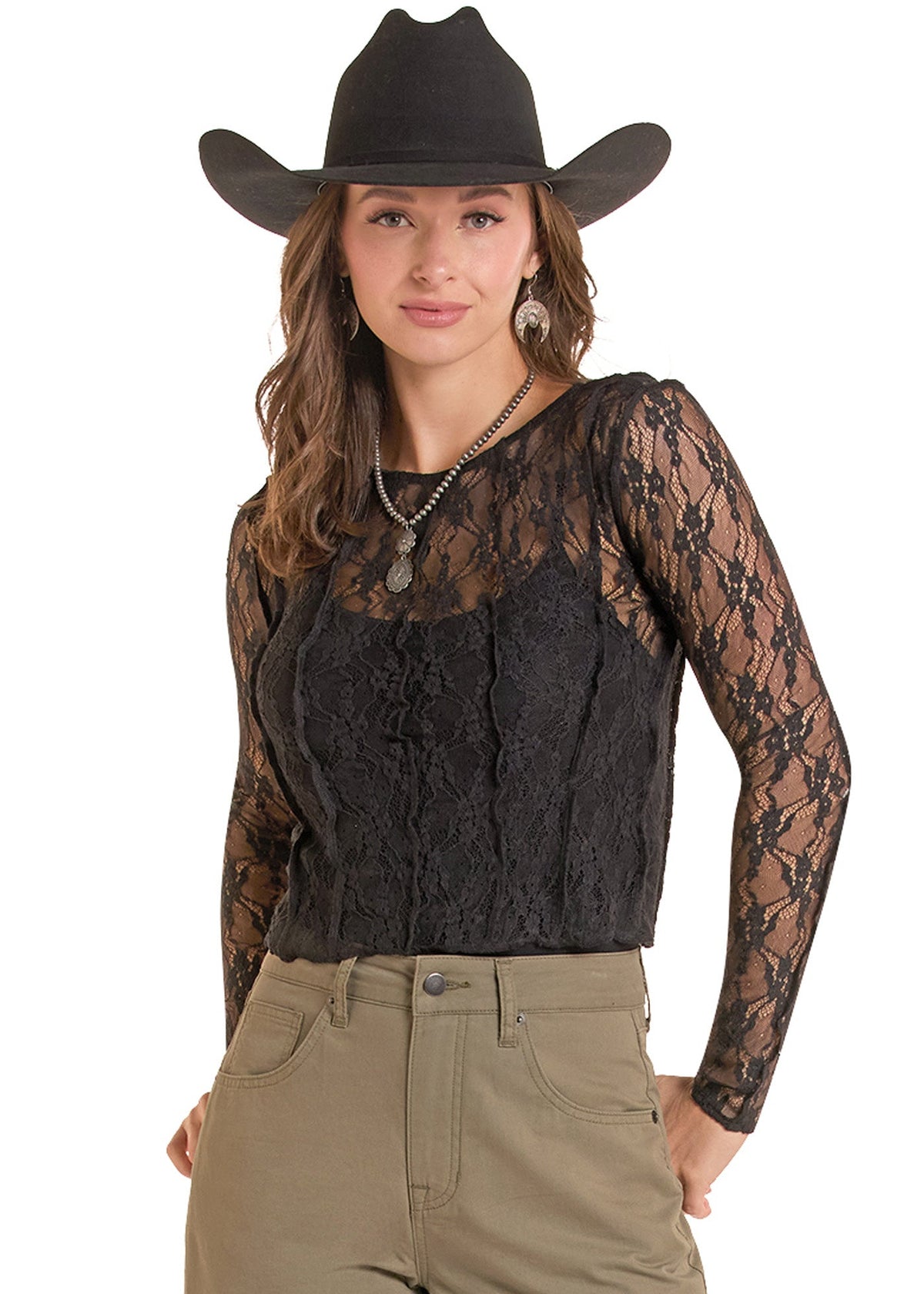 A woman modeling a black lace long-sleeve top with a textured front panel, paired with khaki pants and a black cowboy hat, against a solid white background.