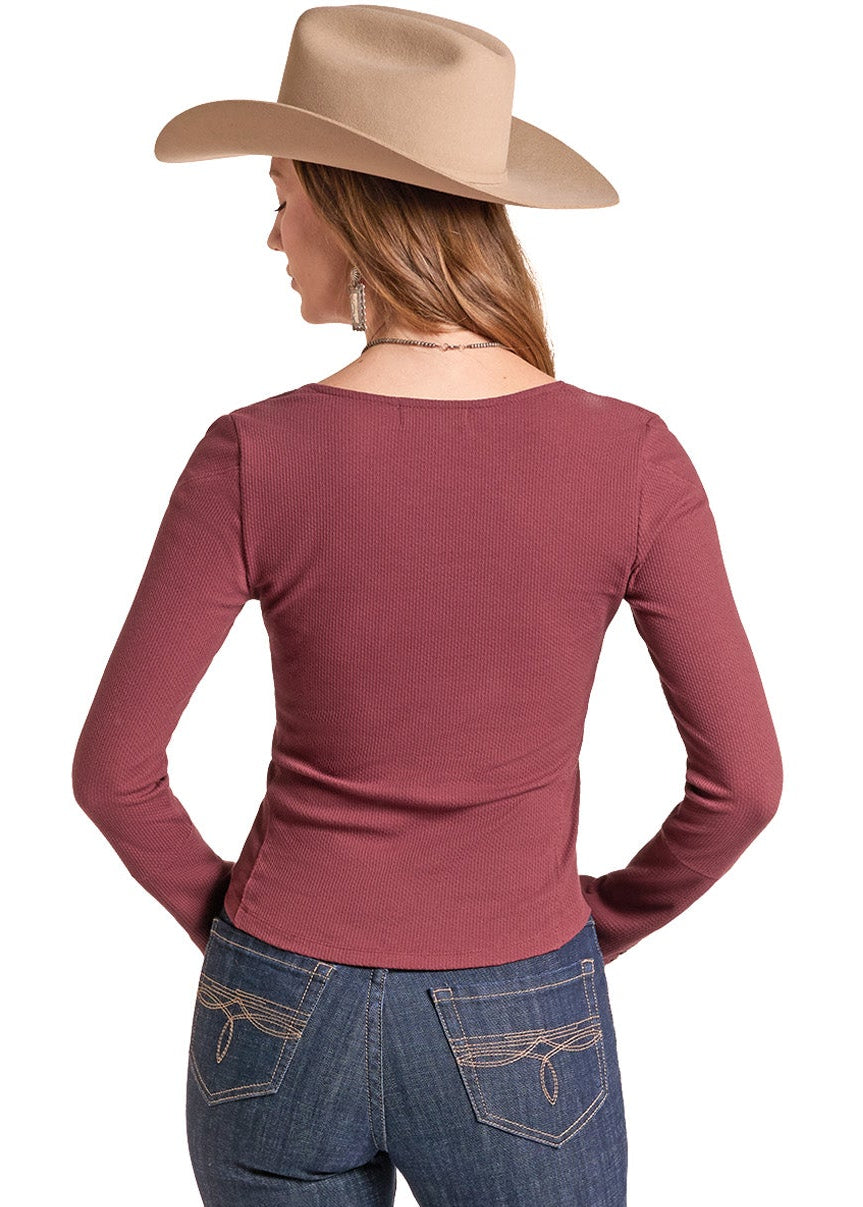 A woman shown from the back wearing a fitted long-sleeve dusty rose top, blue jeans, and a tan cowboy hat against a plain white background.