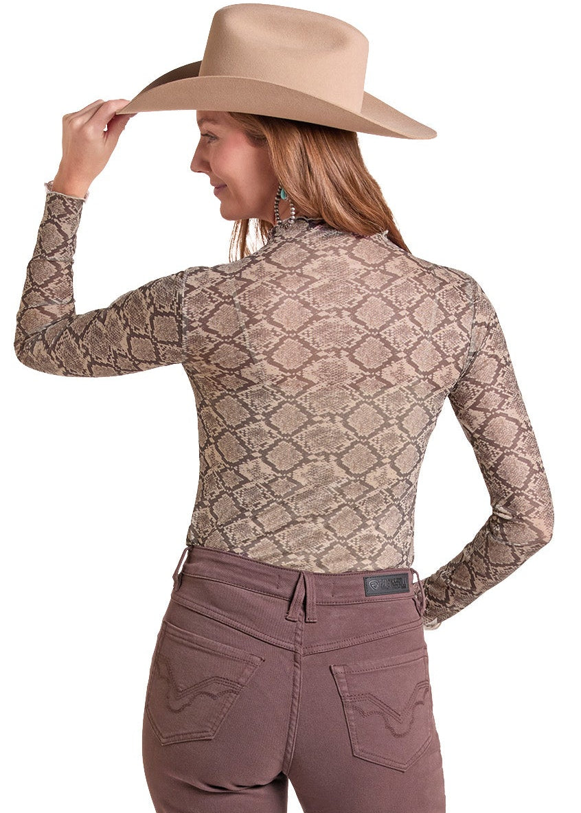 A woman shown from the back wearing a beige snakeskin-patterned long-sleeve top, mauve-brown pants, and a tan cowboy hat.