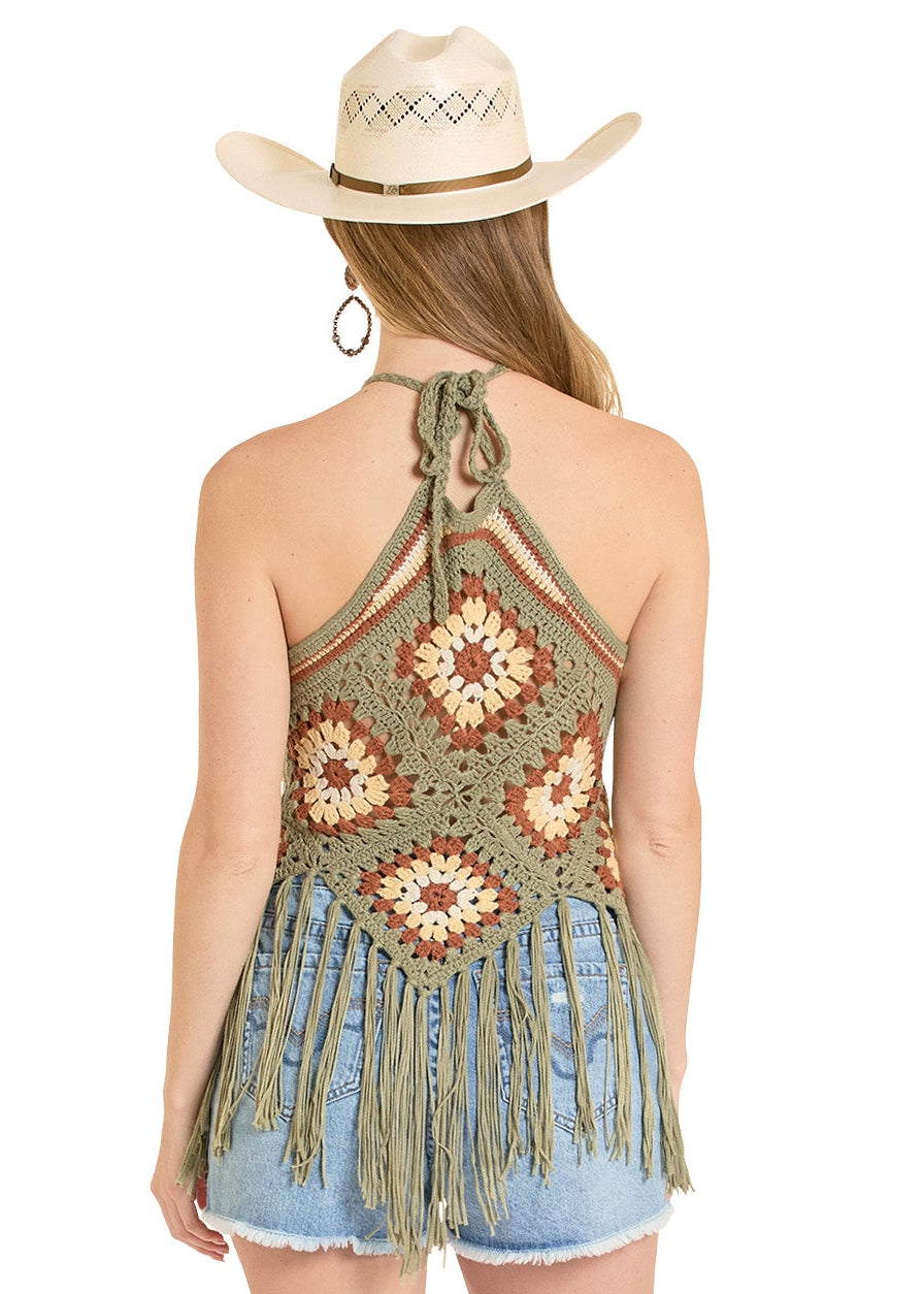 Person wearing a crochet top, denim shorts, and white cowboy boots on a white background