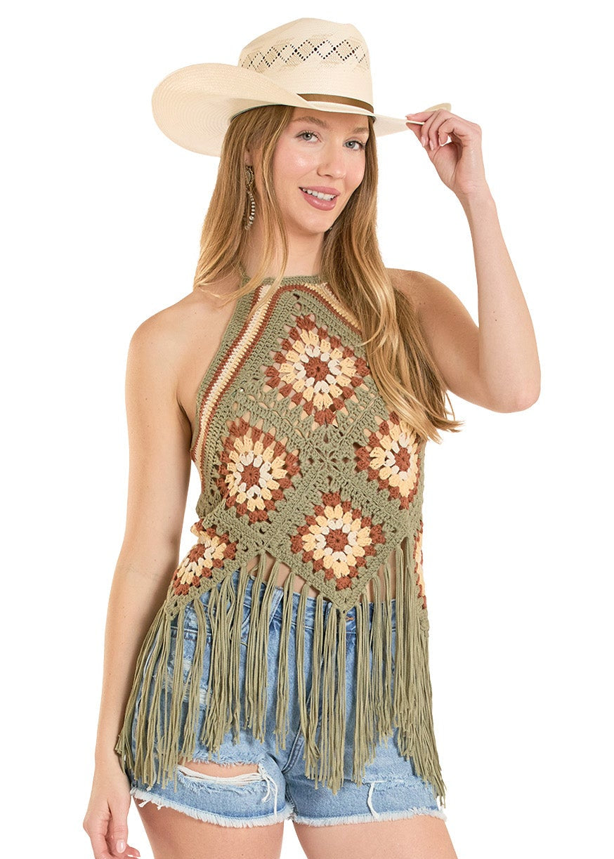 Woman wearing a crochet top, denim shorts, and cowboy boots on a white background