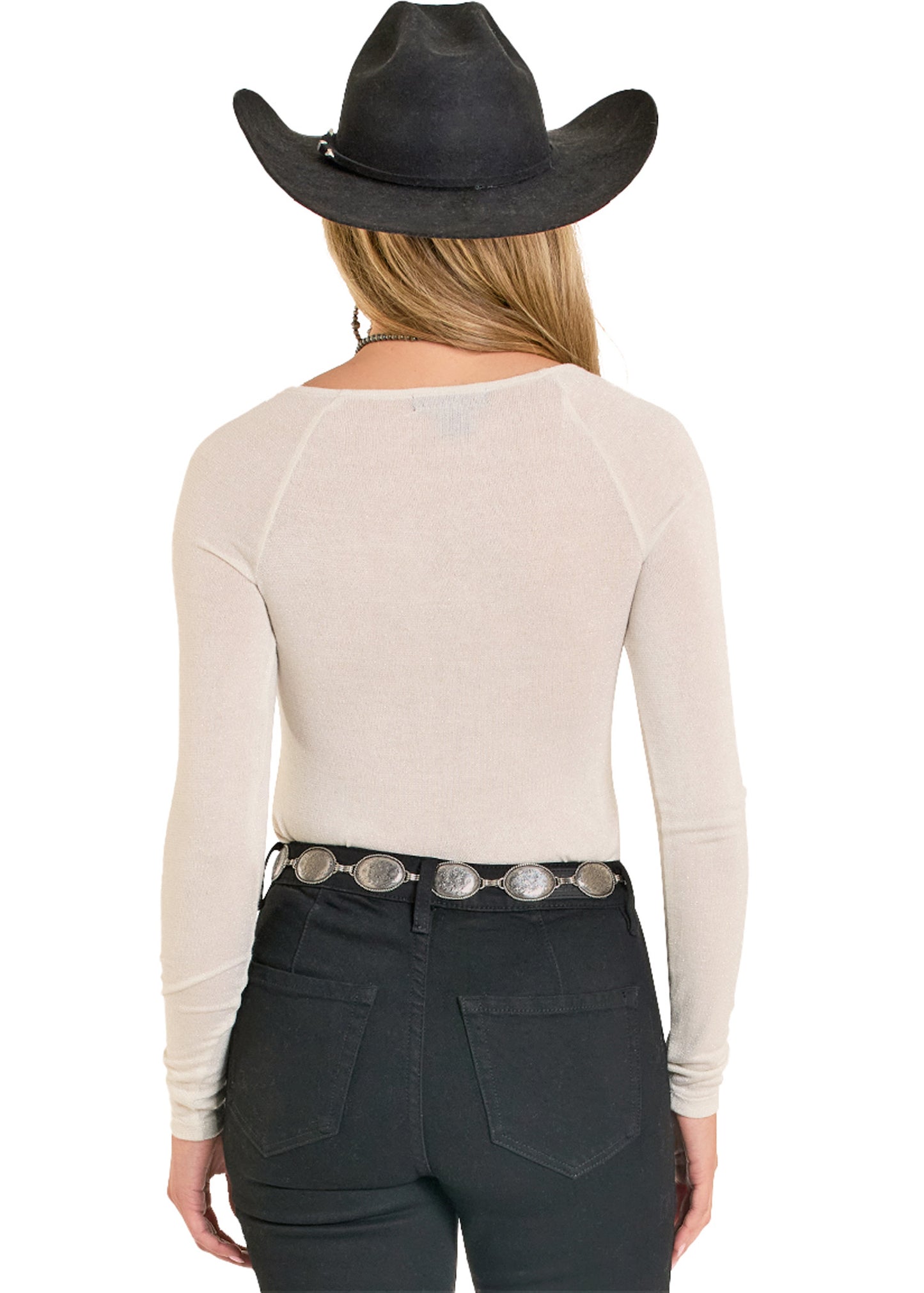 Person wearing a beige long-sleeve top, black pants, and a black cowboy hat on a white background