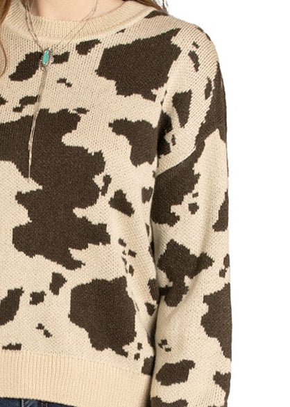 Woman wearing a cow print shirt and jeans with a cowboy hat on a white background