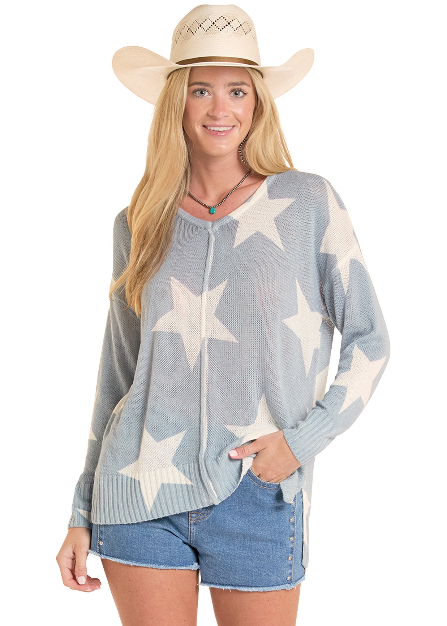 Woman wearing a star-patterned sweater and denim shorts with a cowboy hat on a white background