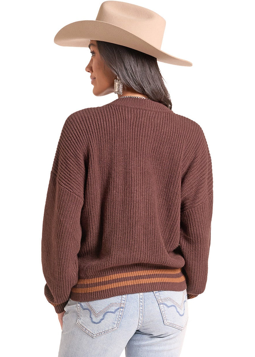 A woman shown from the back wearing a brown ribbed knit sweater, light-wash blue jeans.