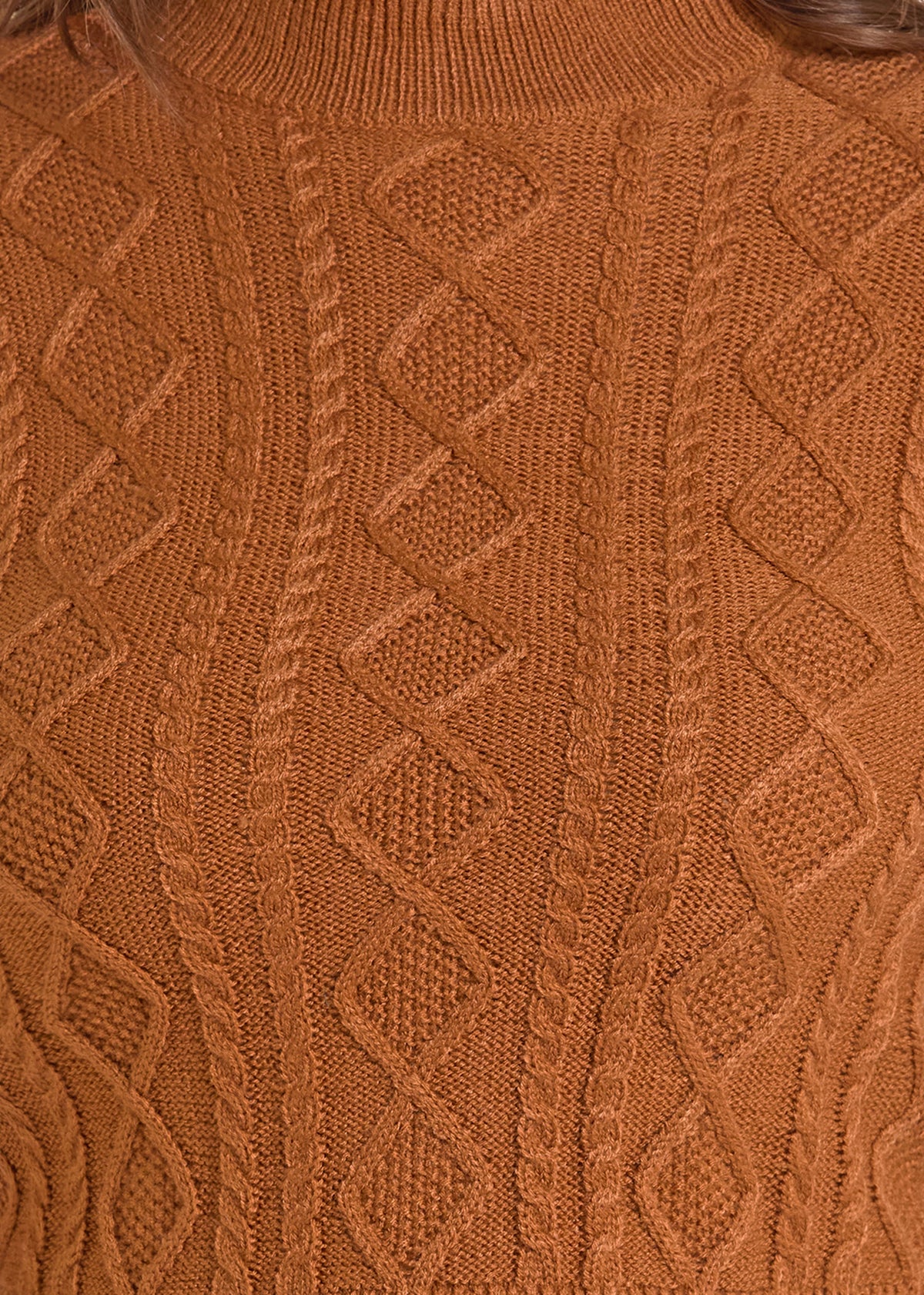 Close-up of a textured cable-knit sweater in a warm rust or burnt orange color, showing detailed knit patterns and ribbed collar.