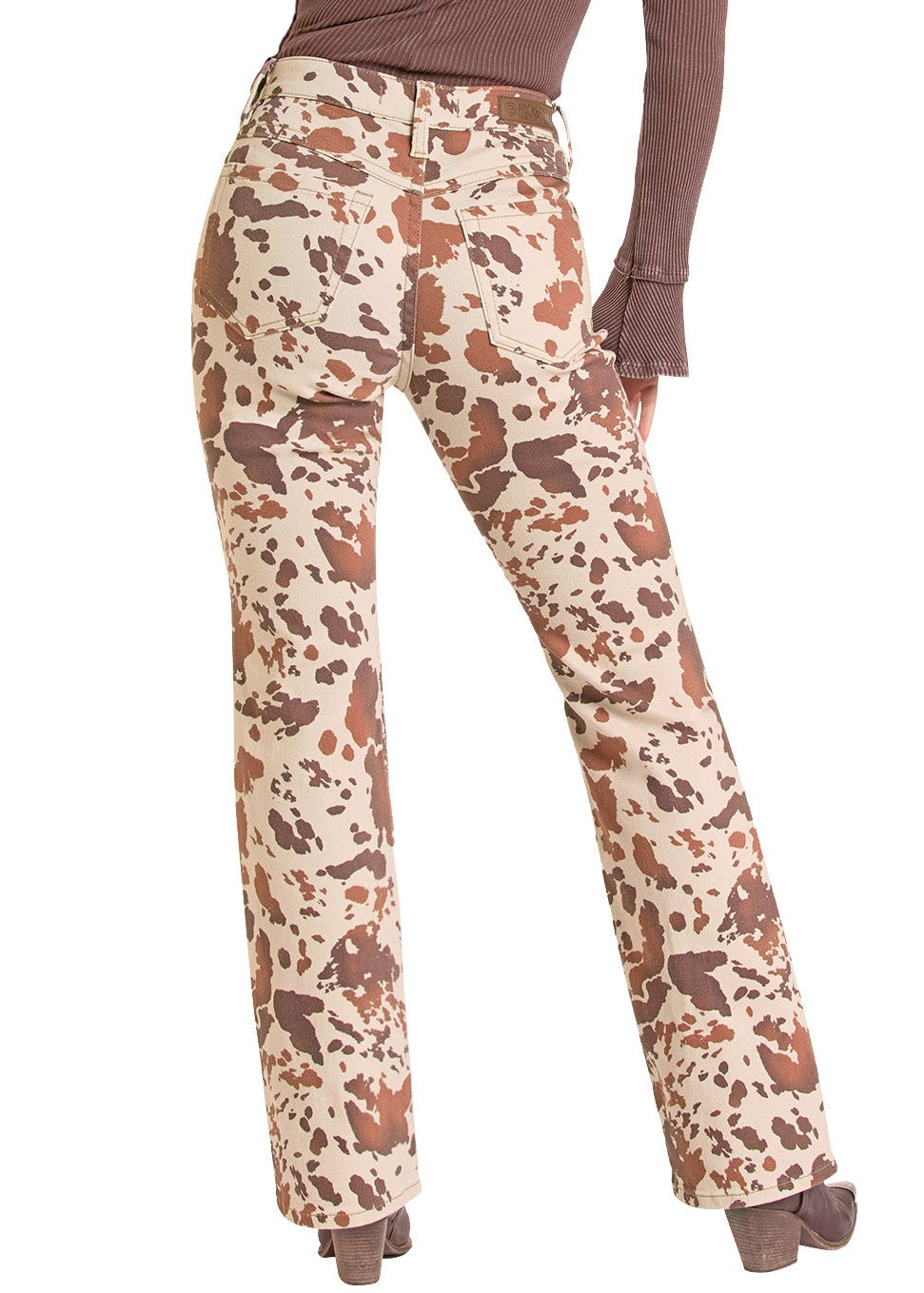 A woman shown from the back wearing a brown long-sleeve top, high-waisted cow-print pants, and a beige wide-brim hat against a plain white background.