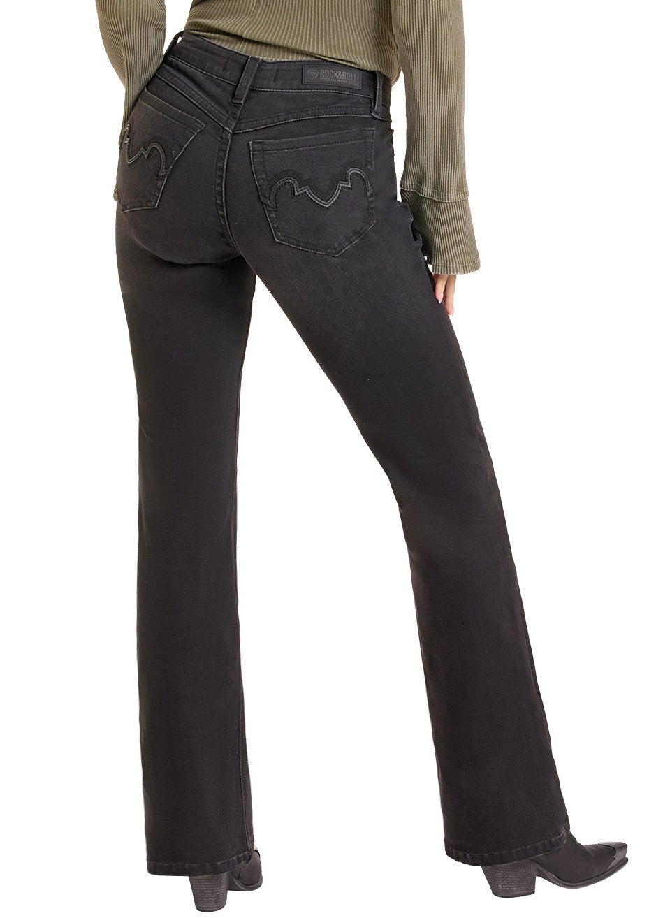 A woman shown from the back wearing a black wide-brim hat, an olive green long-sleeve top, black jeans, and black boots against a plain white background.