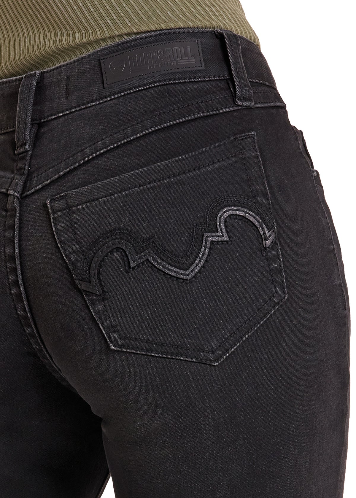 Close-up of the back waistband and pocket area of black denim jeans worn by a model, showing a ribbed olive green top at the waistband and a decorative stitched wave motif on the back pocket.