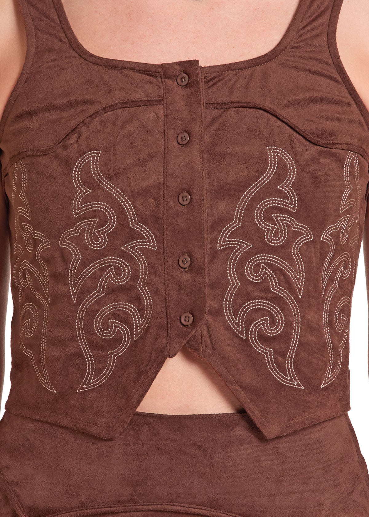 A close-up of a brown faux-suede sleeveless top with a button-front center panel and white embroidered scrollwork on both sides.