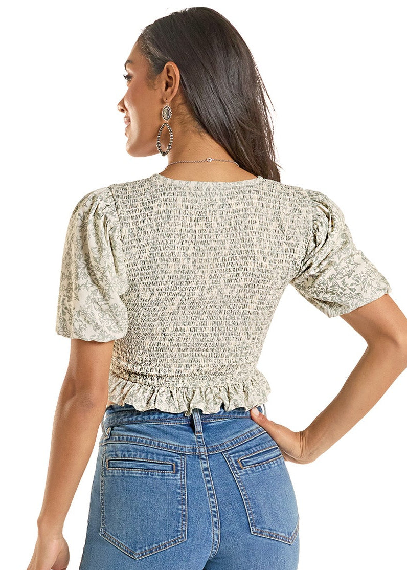 Woman wearing a patterned top and blue jeans on a white background