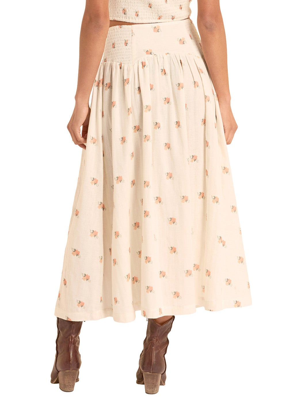 Woman wearing a beige dress with floral pattern and a matching hat on a white background
