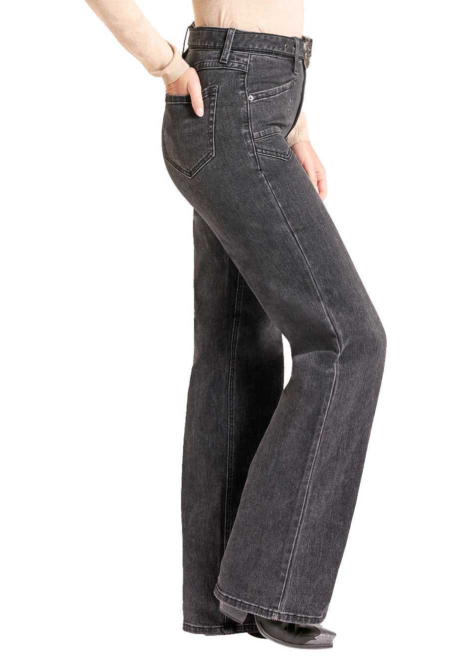 A woman modeling dark gray flare jeans with a beige long-sleeve top and a black cowboy hat, shown from the side against a plain white background.