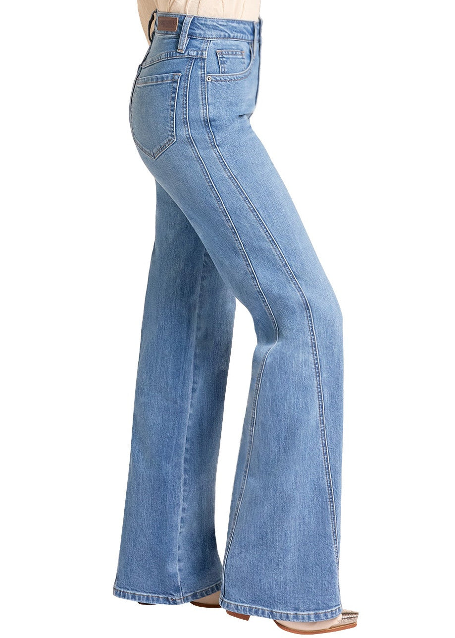 A woman modeling a pair of light-wash blue flare jeans with a beige long-sleeve top and a tan cowboy hat, shown from the back against a plain white background.