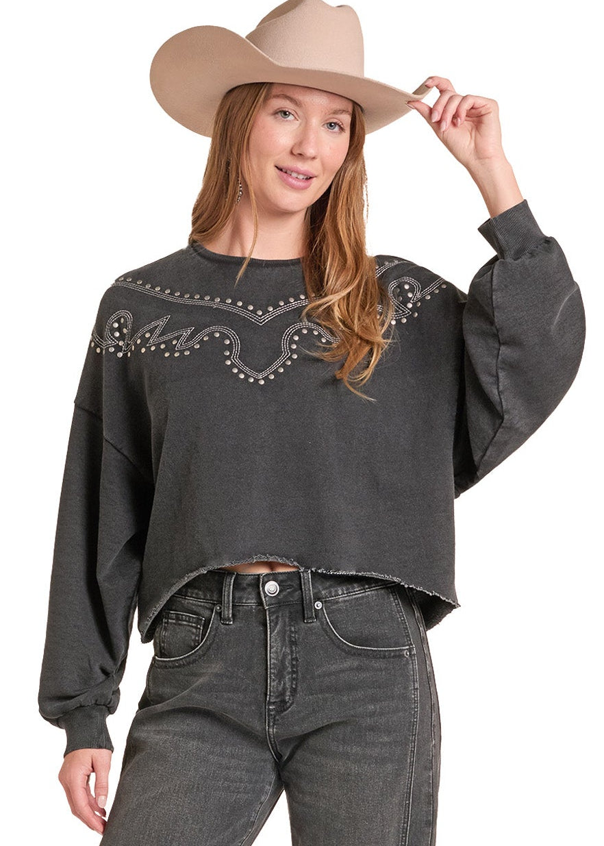 A woman modeling a dark charcoal gray cropped sweatshirt with western-style embroidery and bead details, paired with dark gray jeans.