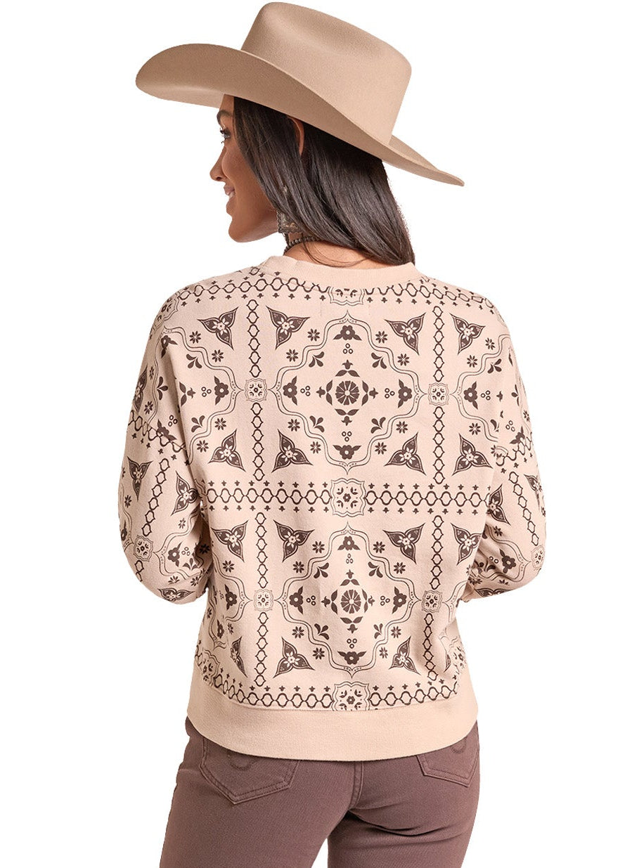 A woman shown from the back wearing a beige patterned knit sweater, brown flared pants, and a tan cowboy hat against a plain white background.