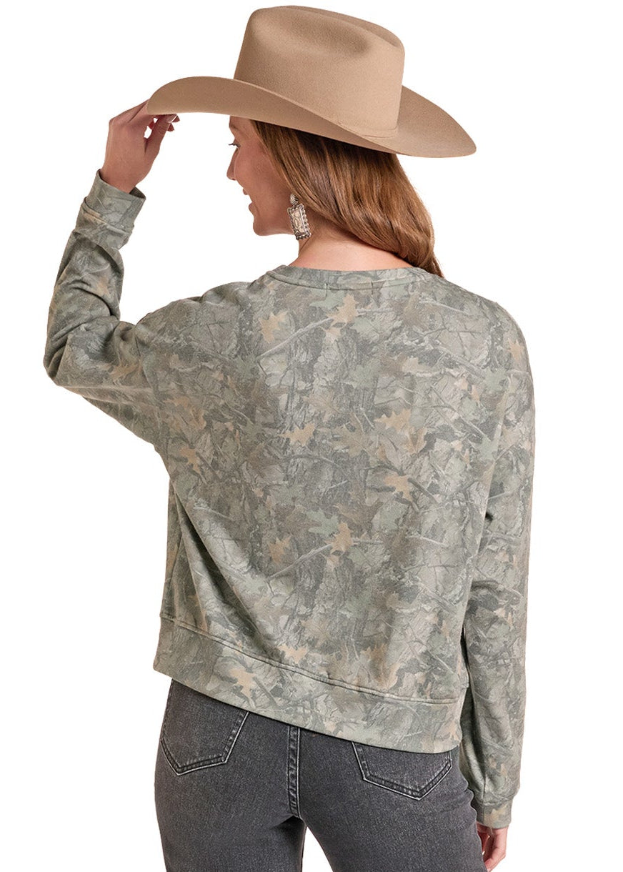 A woman shown from the back wearing a sage green and gray camouflage patterned long-sleeve crop top, dark gray jeans, and a tan cowboy hat against a white background.
