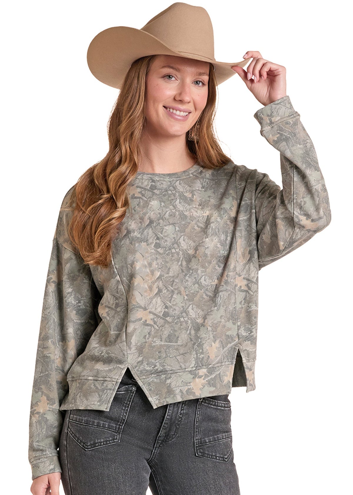 A woman wearing a long-sleeve camouflage sweatshirt, dark gray jeans, and a tan cowboy hat, posing against a solid white background.
