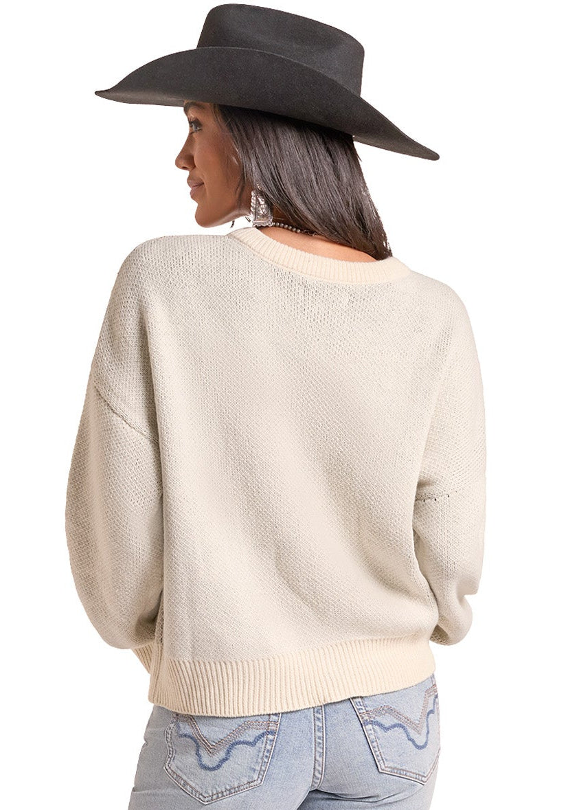 A woman shown from the back wearing a cream-colored knit sweater, light-wash blue jeans, and a black wide-brim hat against a plain white background.