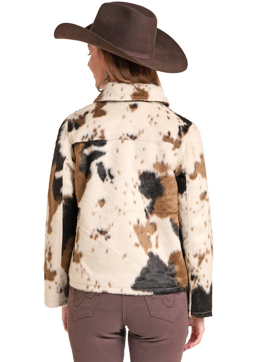 A woman shown from the back wearing a brown cowboy hat, a long-sleeve collared shirt with a brown, black, and cream cow-print pattern, and brown flared pants, set against a plain white background.