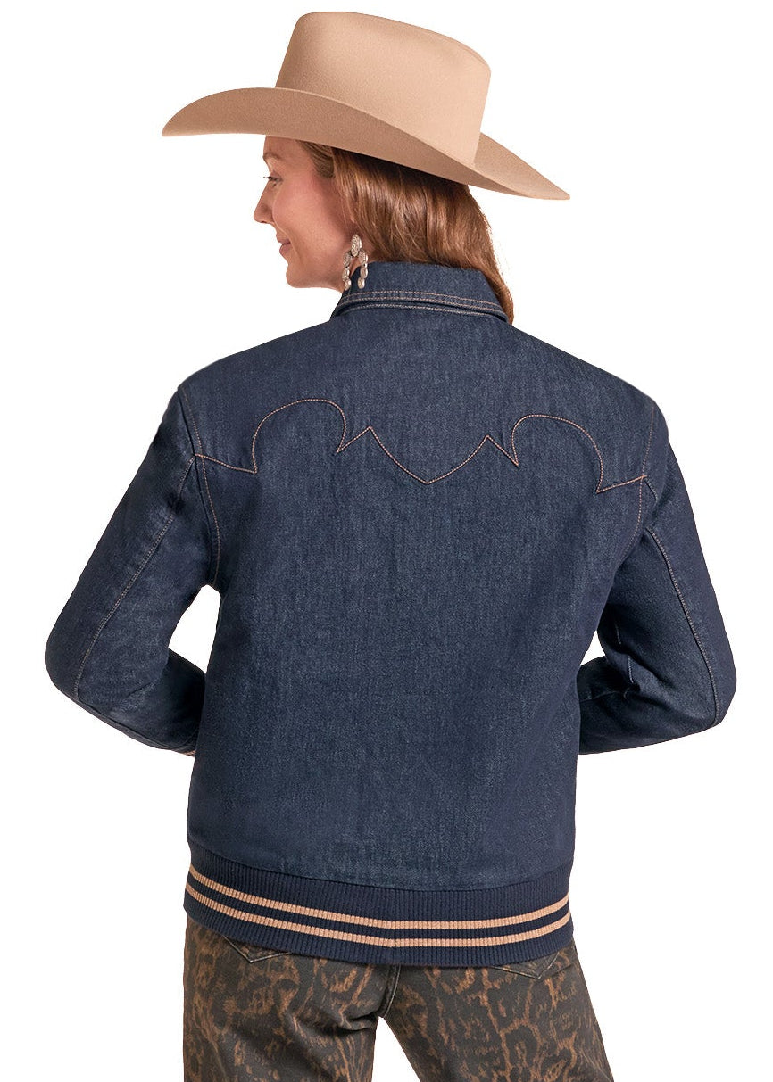 A woman shown from the back wearing a dark blue denim jacket with western-style stitching, brown patterned pants, and a beige cowboy hat against a plain white background.