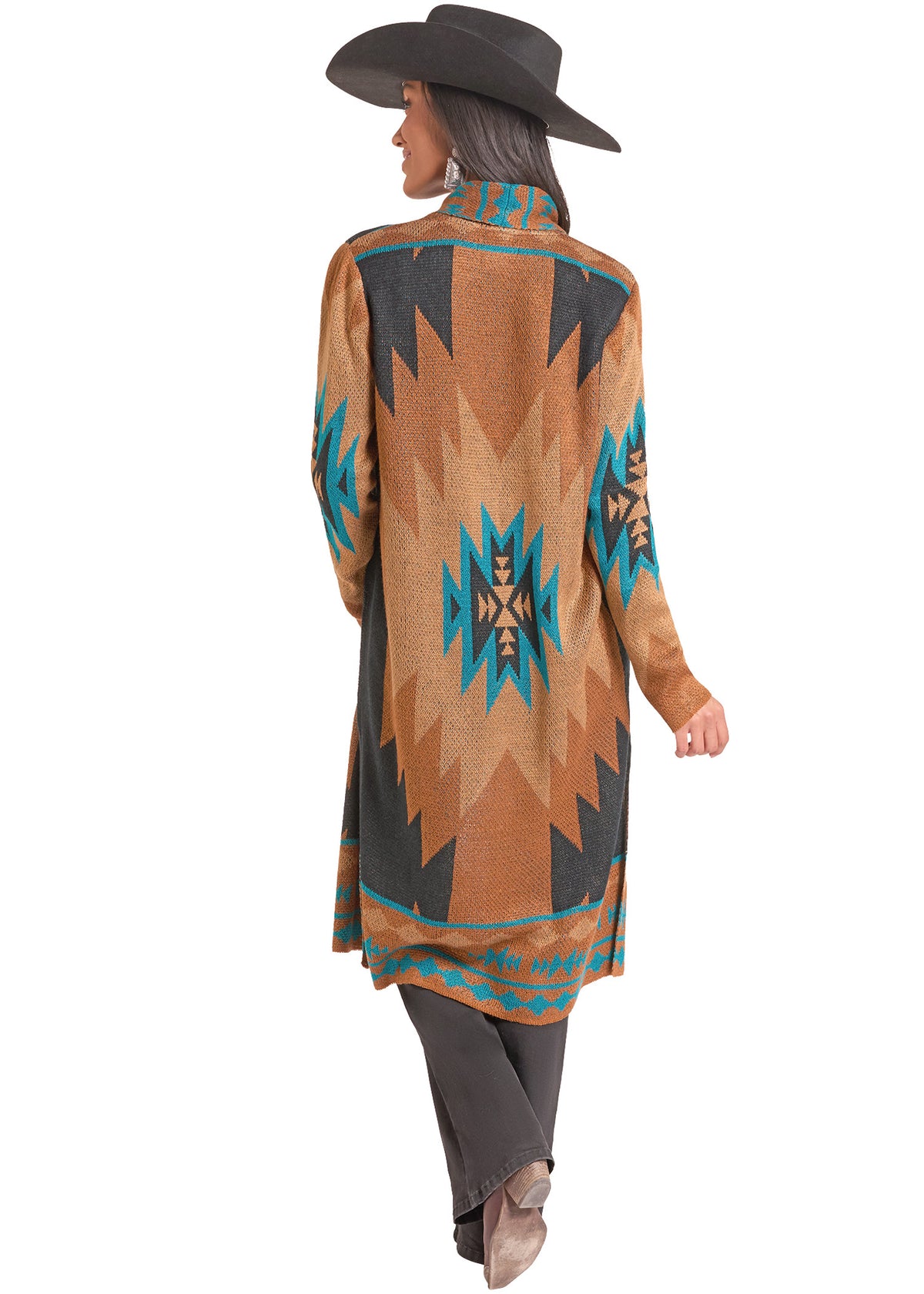 A woman shown from the back wearing a long-sleeve, high-neck patterned cardigan or poncho in tan, black, and turquoise, along with dark pants and a black wide-brim hat, against a plain white background.