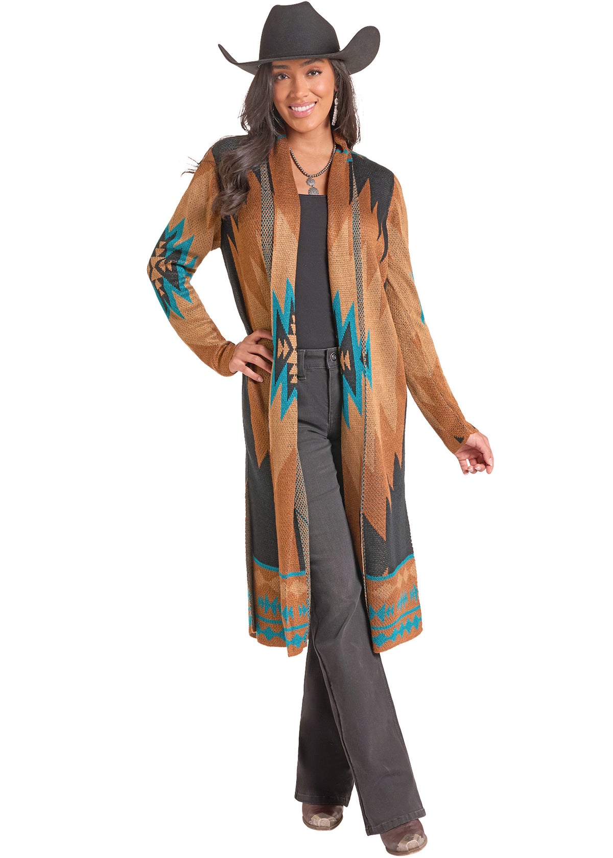 A woman modeling a long tan leather-like cardigan with Southwestern geometric patterns in turquoise, brown, and black, worn over a black top and dark gray pants, against a plain white background.