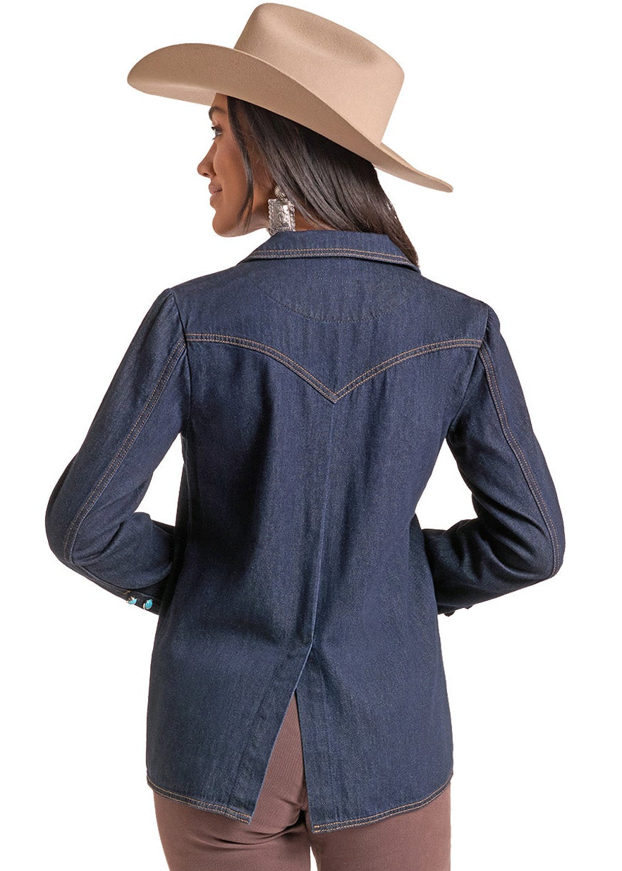A woman shown from the back wearing a dark blue denim western-style jacket with contrast stitching, brown pants, and a beige cowboy hat, set against a plain white background.