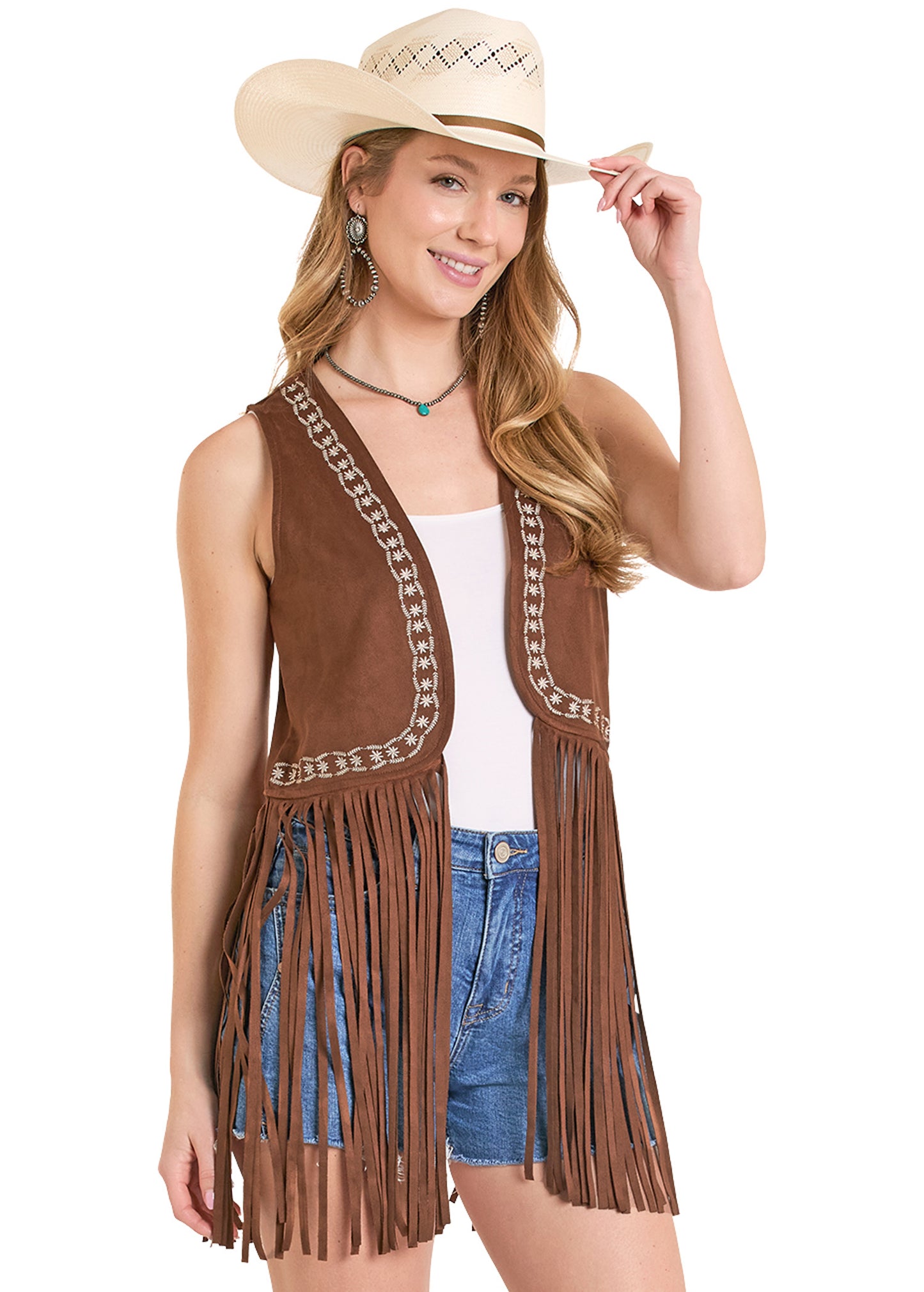 Woman wearing a brown fringe vest, white top, and denim shorts with a beige cowboy hat.