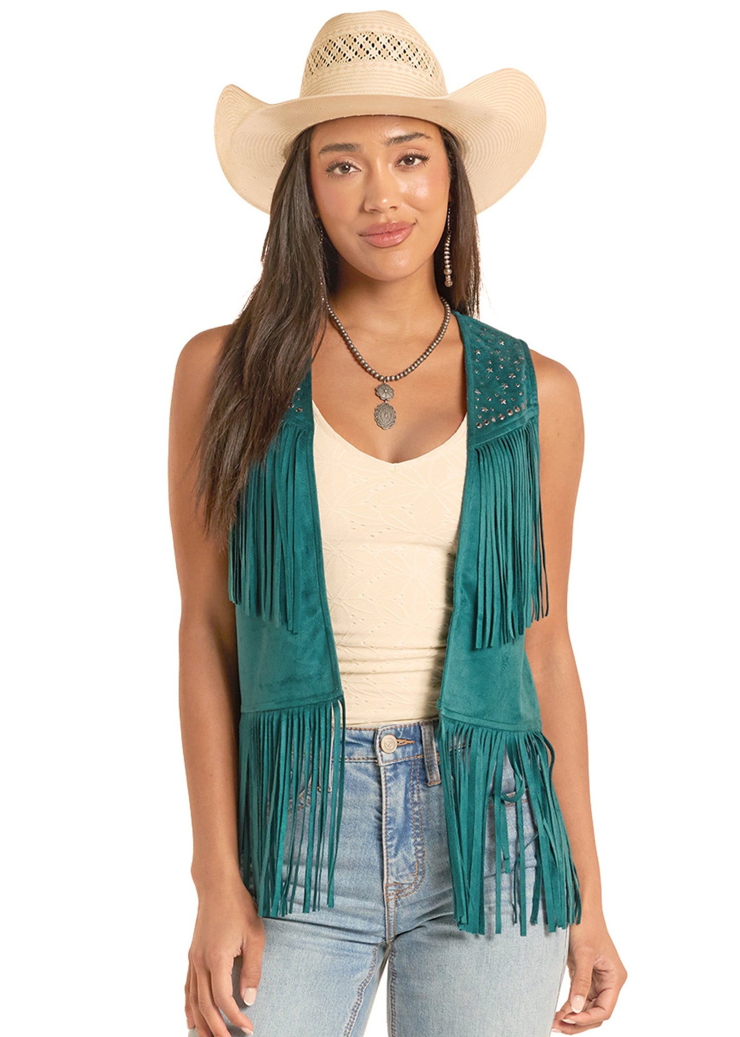 Woman wearing a teal fringe vest, beige hat, and light blue jeans on a white background