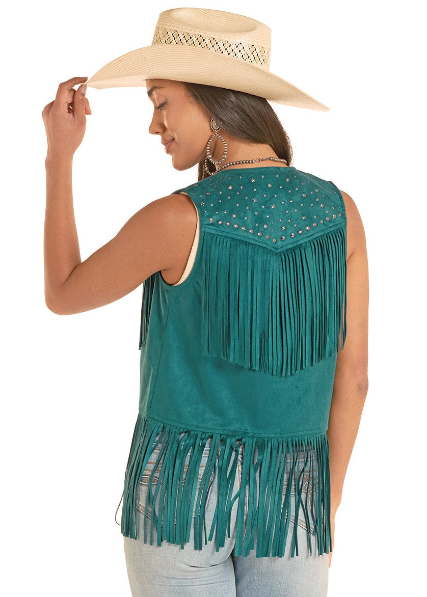 Woman wearing a teal fringe top and light blue jeans on a white background