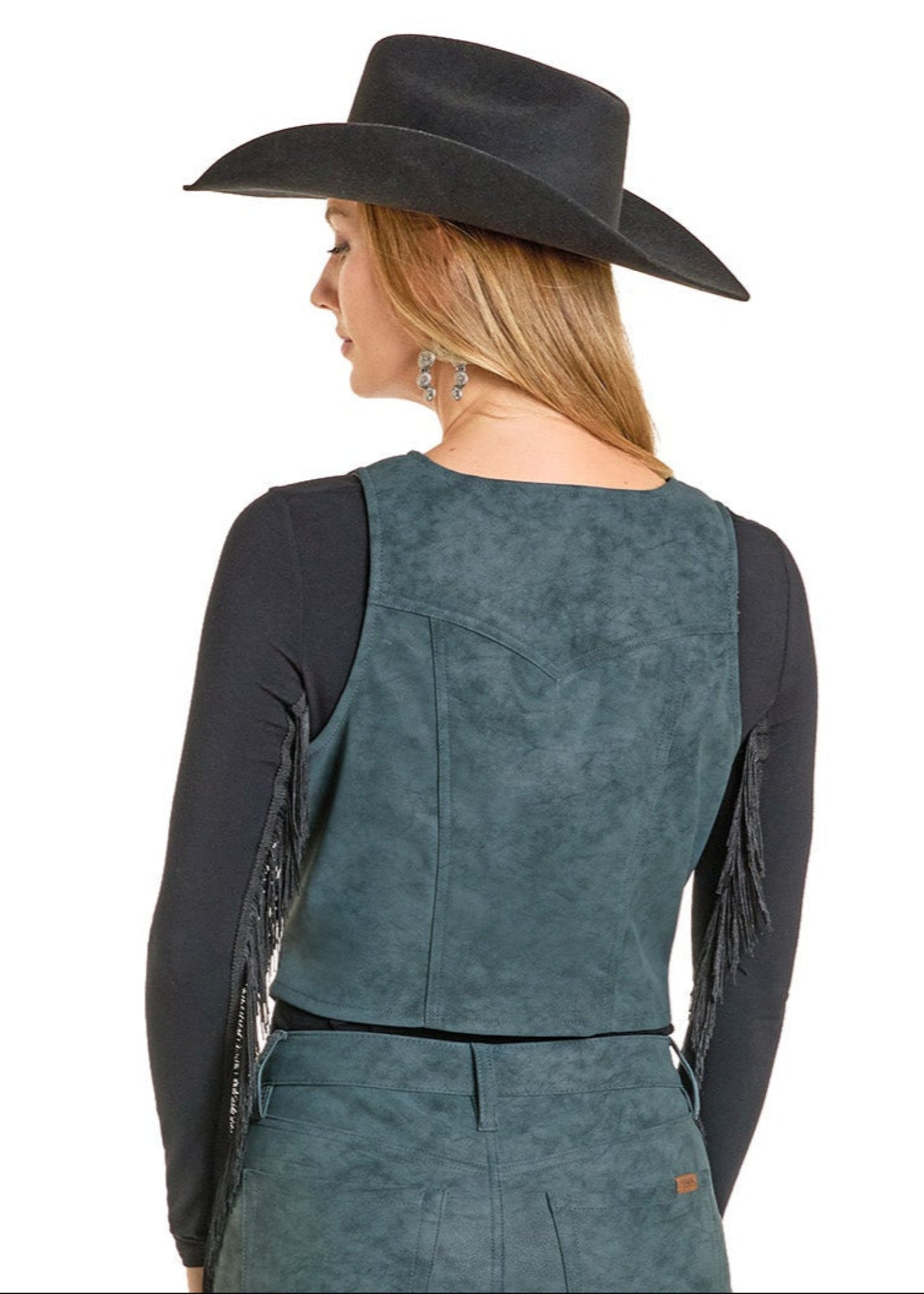 Person wearing a teal suede vest with fringe details and a black cowboy hat on a white background