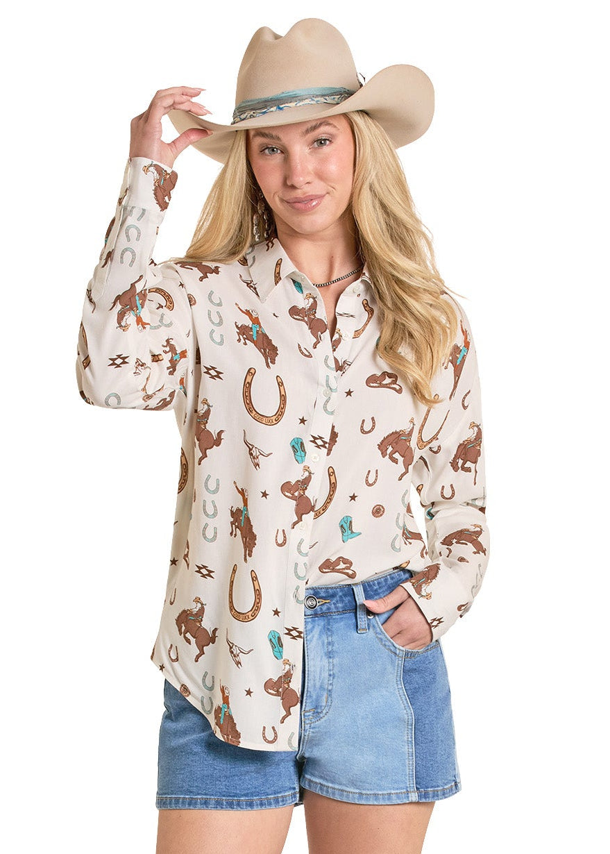 Woman wearing a patterned blouse, denim shorts, and cowboy boots on a white background