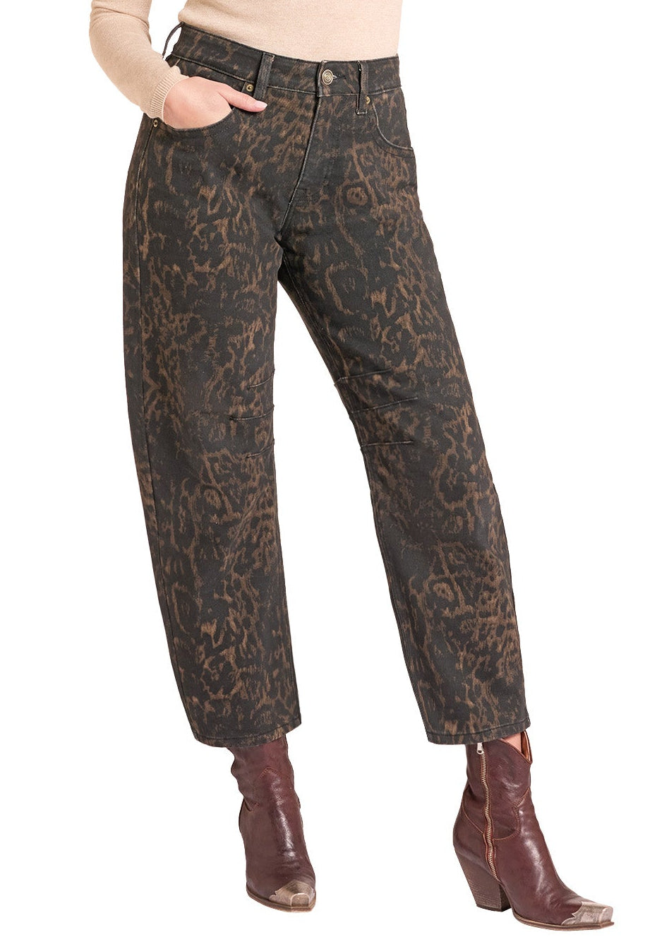 A woman modeling a pair of dark brown and black snakeskin print jeans, styled with a beige long-sleeve top, a tan cowboy hat, and brown leather cowboy boots against a white background.