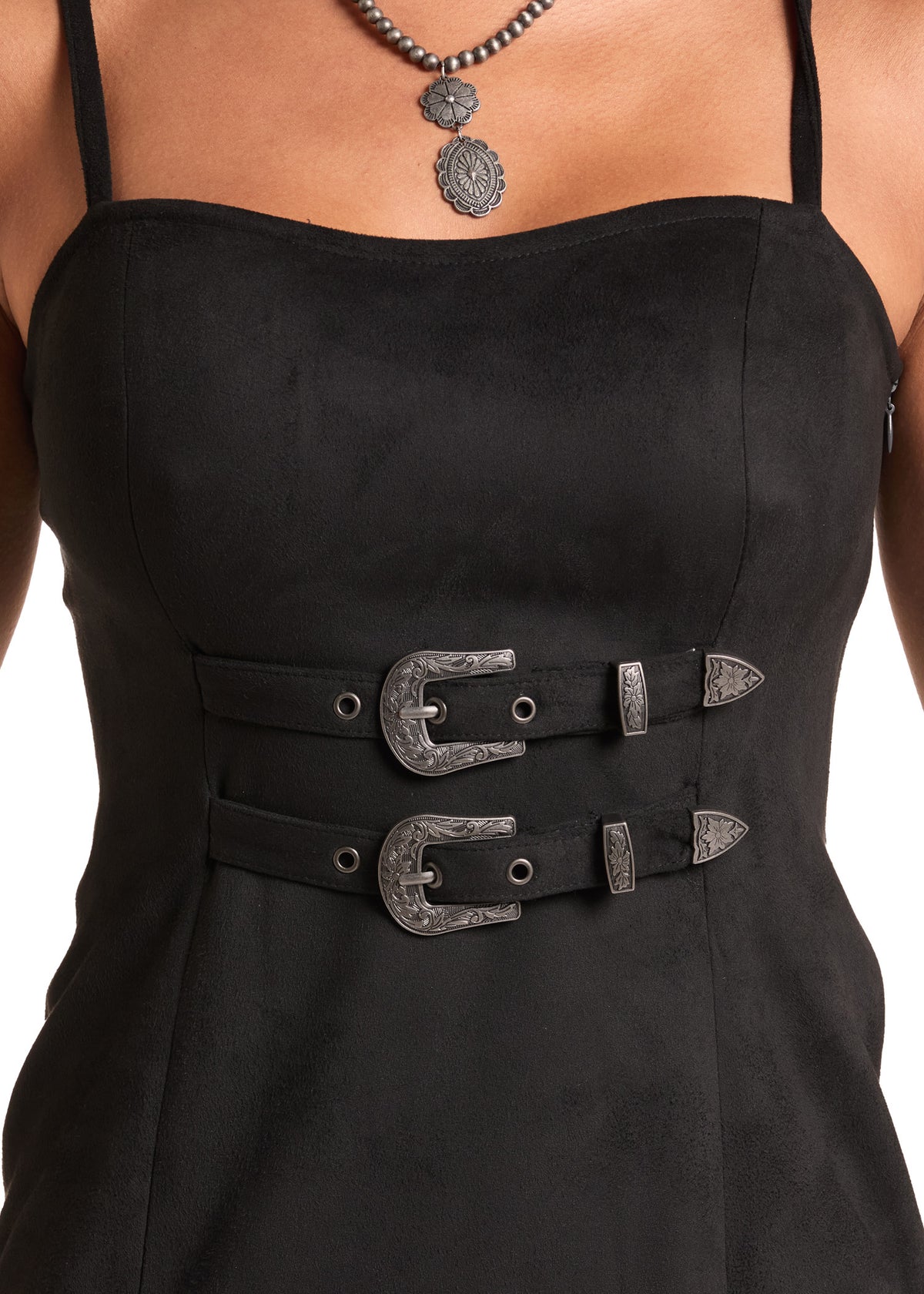 Close-up of a black sleeveless dress with a structured sweetheart neckline and two wide decorative waist straps featuring large silver-toned buckles, worn by a model.