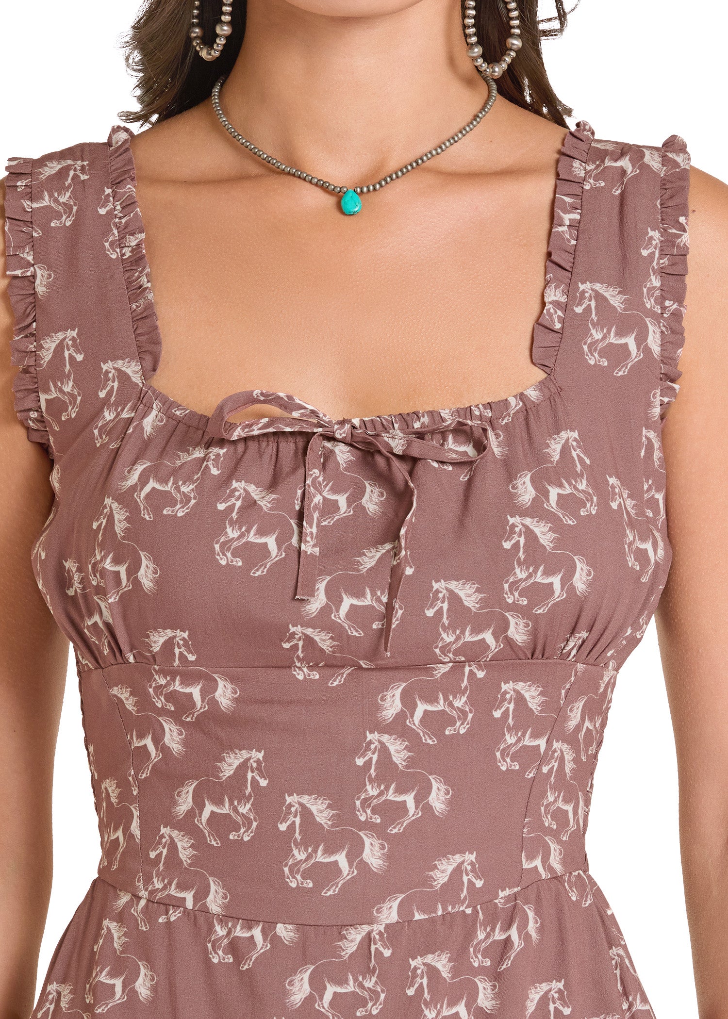 Woman wearing a brown dress with horse pattern and turquoise necklace.